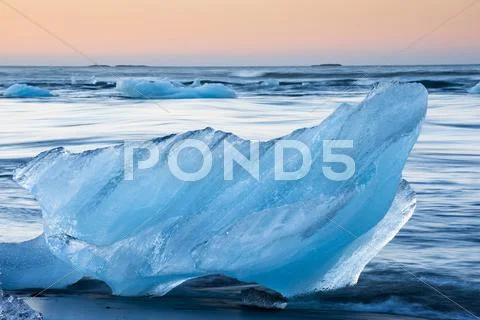 Block Of Ice On A Black Beach Being Lapped By The Sea Jokulsarlon Glacier