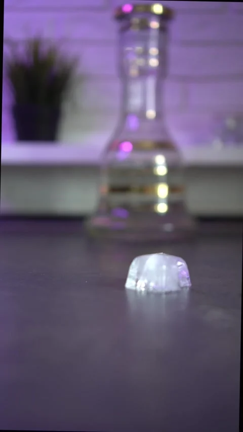 Block of ice slides across table to hookah glass base Stock-Footage 164462158