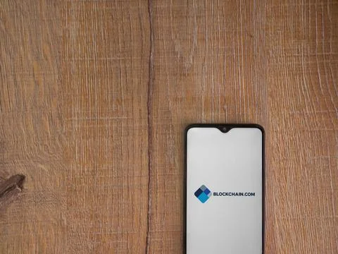 Blockchain.com app launch screen on smartphone on wooden background Stock Photos
