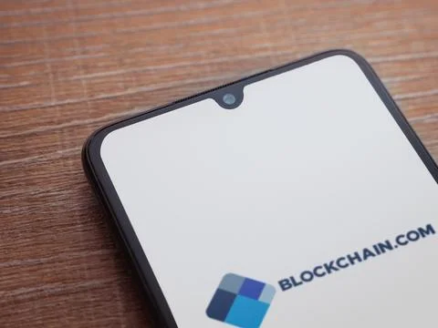 Blockchain.com app launch screen on smartphone on wooden background Stock Photos