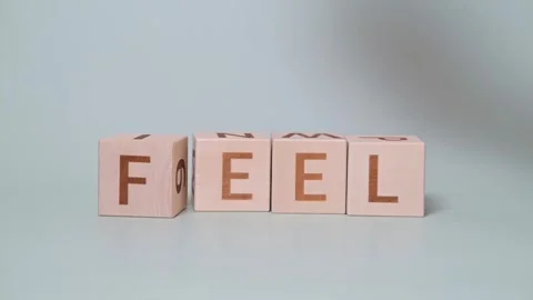 Blocks are placed on a light surface to form the word "feel." A hand strikes Vidéo 338187589
