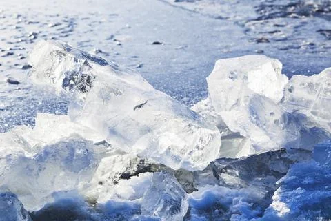Blocks of ice illuminated by the sun at the edge of an ice hole in a frozen lake Stock Photos