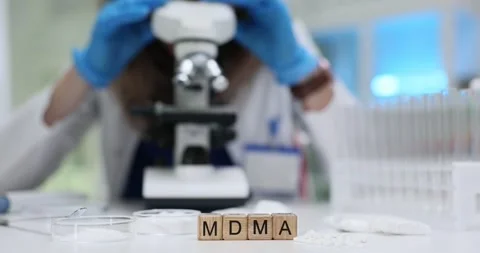 Blocks with MDMA on desk with scientist at work with microscope Stock Footage 314105088