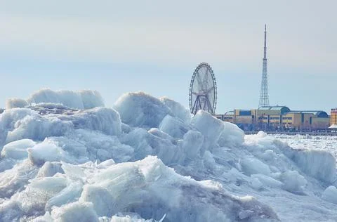 Blocks of river ice on the background of the Ferris wheel. Stock Photos
