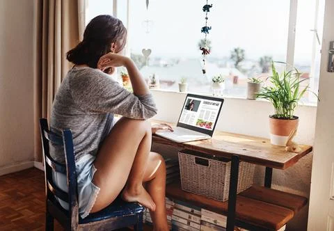 This blog is really inspiring. a young woman using her laptop while sitting at Stock Photos