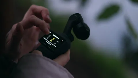 Blogger adjusting settings on a compact gimbal camera Video stock 336690656