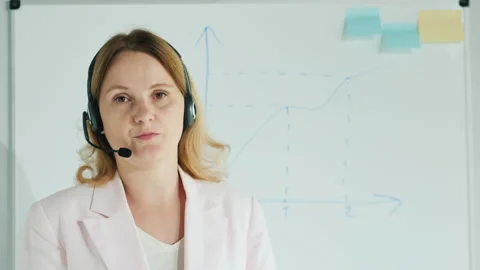Blogger in headset talks to the camera against the background of a board with Видео 146325777