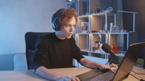 The blogger plays during the stream, listens to music and dances with his head. Stockbeeldmateriaal 204075985
