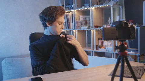 The blogger puts on a wired microphone, corrects the camera, waves at the camera 库存影片 204075500