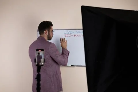 A blogger is recording a video tutorial for his audience by writing Stock-Fotos