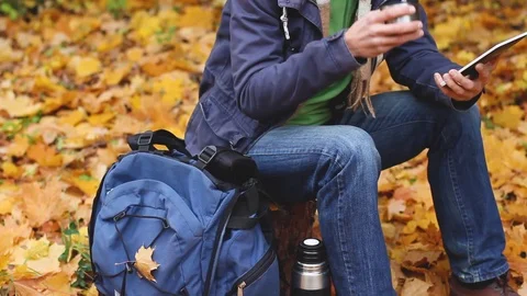 Blogger sits in forest, drinks and working on tablet, autumn, panoramic camera Видео 103239283