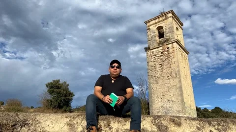 Blogger talking on camera beside Ochate church tower Stock Footage 321341145