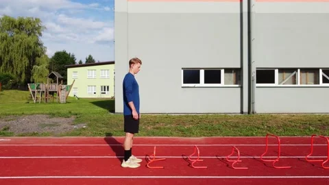 Blond athlete in a blue T-shirt develops his dynamic strength by jumping over hu Video stock 205590153