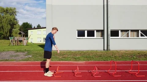Blond athlete develops his dynamic strength by jumping over hurdles 動画素材 205595194