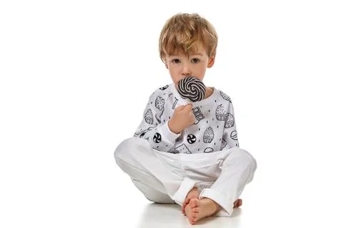 Blond baby boy in pijama with candys Stock Photos