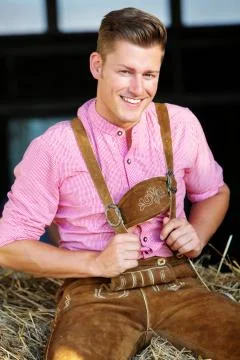 Blond bavarian man sitting on a haystack Stock Photos