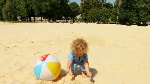 A blond boy 2 years old plays on the beach with boll on a Sunny summer day.4K Stock Footage 133902623