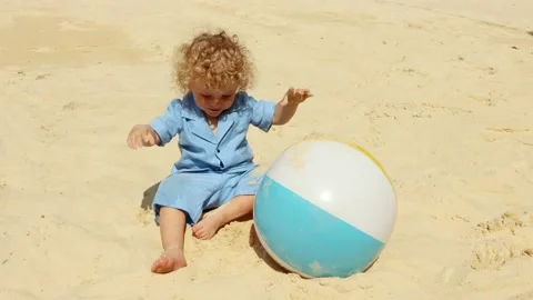 A blond boy 2 years old plays on the beach with boll on a Sunny summer day.4K Stock Footage 133907582