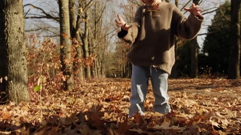 A blond boy cheerfully throws up fallen leaves. Stock Footage 262760285