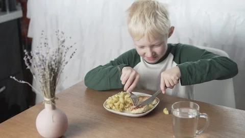 The blond boy dines at home with pasta and meatballs Stock Footage 125513357