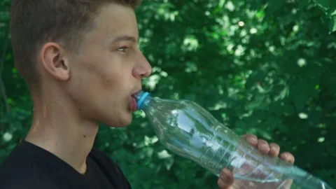 Teen boy drinks water from a bottle, Stock Video