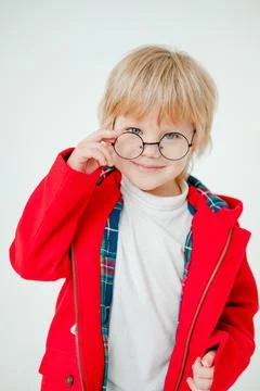 Blond boy with glasses. A beautiful blonde child. Boy in a red coat. Stock Photos
