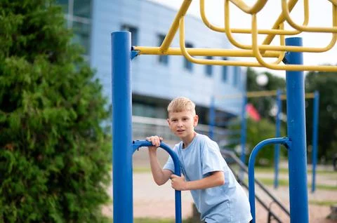 Blond boy hanging on monkey bars at outdoor playground Stock Photos