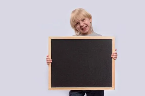 Blond boy holding blackboard and smiling. Copy space. Template. Mockup. Stockfoto's