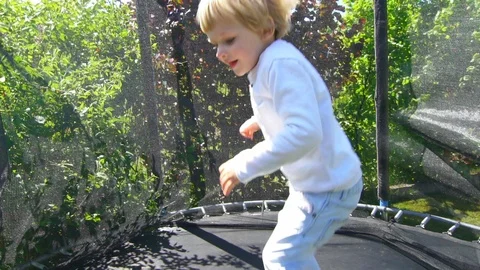 Blond boy jumping on trampoline in back yard. Slow motion Stock Footage 109591699