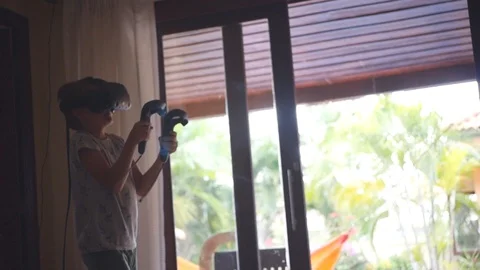 The blond boy plays an active game in virgin glasses, jumps around the room Stock Footage 88799569