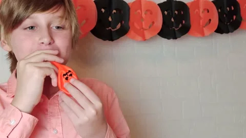 A blond boy smiling Inflating the orange pumpkins balloon, Halloween at home Stock Footage 141038747