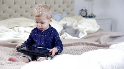 Blond boy with tablet in bright bedroom.FULL HD.tracking shot. Stock Footage 73967836
