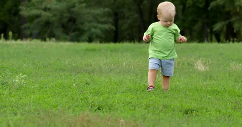 Blond boy taking first steps at playground, learning to walk Stock Footage 235899576