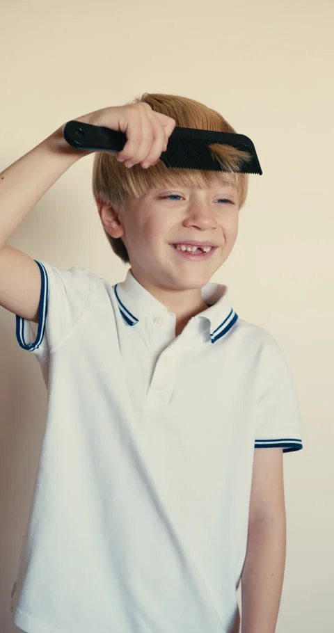 A blond boy with thick, beautiful light hair is combing himself with a large 스톡 동영상 323108346