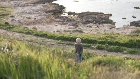 A blond boy walking by the sea. Stock Footage 106864804