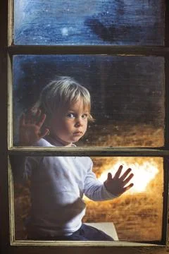 Blond child behind the window, looking outside at  moon Fotos Stock