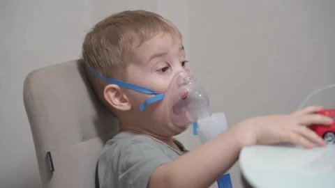 Blond child inhales vapors containing medications from inhaler. Stock Footage 331663000