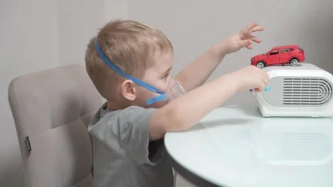 Blond child inhales vapors containing medications from inhaler. Stock Footage 331663111