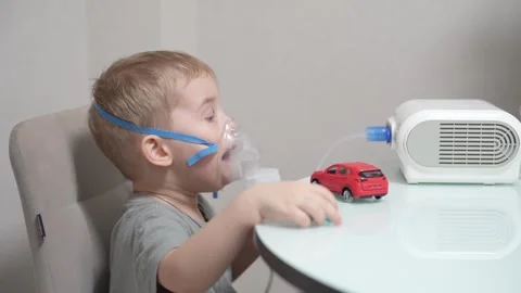 Blond child inhales vapors containing medications from inhaler. Vídeo Stock 331663158