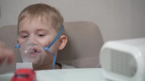 Blond child inhales vapors containing medications from inhaler. Stock Footage 331663244