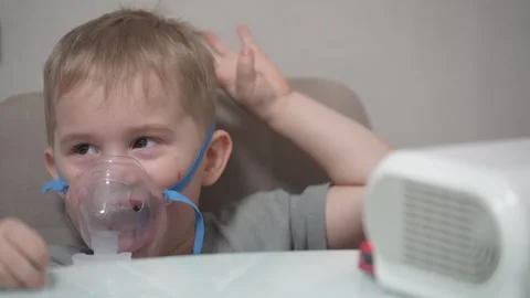 Blond child inhales vapors containing medications from inhaler. Stock Footage 331663260