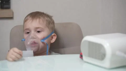 Blond child inhales vapors containing medications from inhaler. Stock Footage 331663266