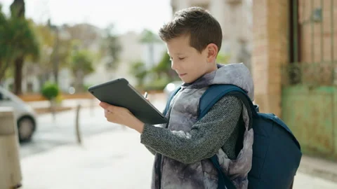 Blond child student using touchpad standing at street Stock Footage 189955324