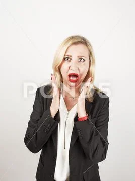 Blond female teacher wearing a strict suit keeping hands on head, terrified i Stock Photos