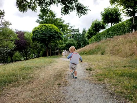 Blond guy with a briefcase behind his back stomping on the path in the park Stock Photos