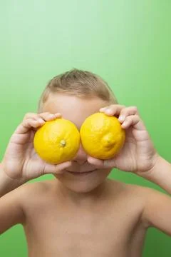 Blond-haired 7-year-old boy with two lemons over his eyes Stock Photos