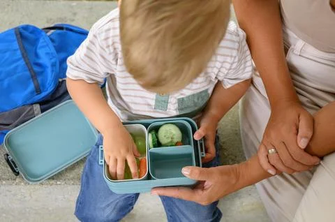 Blond-haired boy holding container of food. back to school. homemade meals. Foto stock