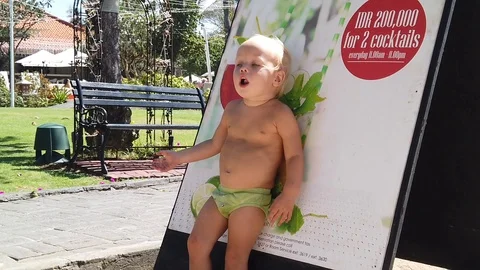 A blond joyful two-year-old boy is dancing next to a restaurant's sign.  Stock Footage 109534653