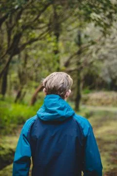 Blond man puts on a colourful jacket in rainy and cold weather. A walk on the Foto stock