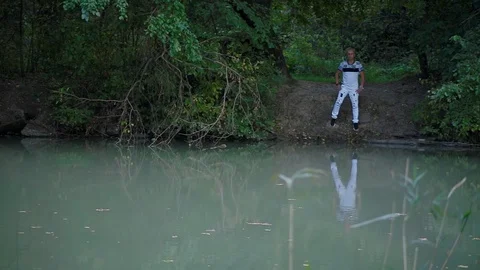 Blond man stands on other side of river and frame includes slim woman Stock Footage 126130423